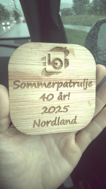 Bordbrikke i finértre, gravert med teksten "LO Sommerpatrulje 40 år! 2025 Nordland". Bordbrikken er oljeimpregnert for å tåle væske. Brikken er designet og produsert av meg på Makerspace Bodø. Logoen tilhører LO.