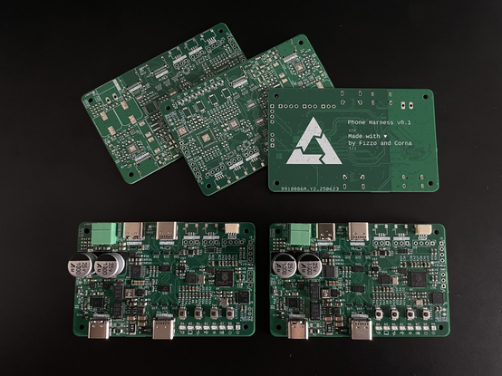 several populated PCBs next to each other on a desk. The back shows the postmarketOS logo and some text "phone harness v0.1 made with love by fizzo and ncorna"