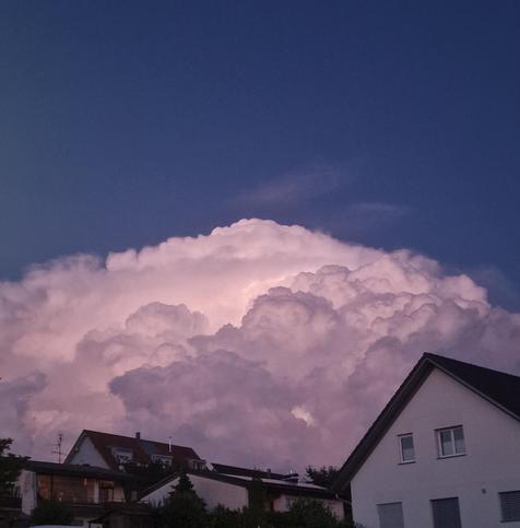 Das Bild zeigt einen beeindruckenden Wolkenformation, die sich majestätisch über ein Wohngebiet erstreckt. Die Wolke ist dicht und voluminös, mit einer kräftigen Struktur, die in verschiedenen Tönen von Weiß und Rosa leuchtet, was auf die Abendsonne hinweist. Der Himmel um die Wolke herum ist tiefblau, was die Wolke noch hervorhebt. Im Vordergrund sind mehrere Häuser zu sehen, die typisch für eine Wohnsiedlung sind, mit weißen Fassaden und dunklen Dächern. Die Häuser sind in der Nähe der Wolke positioniert, was die Größe und Pracht der Wolke betont. Die Umgebung wirkt ruhig und friedlich, mit einigen Bäumen, die die Häuser umgeben.

Bereitgestellt von @altbot, privat und lokal generiert mit Ovis2-8B