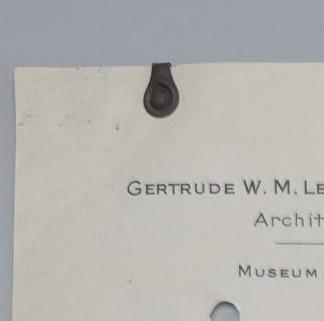 Cream coloured paper with printed sender details. Circular paperclip of tarnished metal positioned at upper right corner.