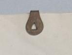 Cream coloured paper with the back of a circular paperclip of tarnished metal with a triangular shaped void at the centre..