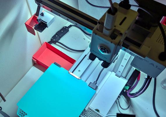 a small 3D printer, brigthly lit up by the custom light mounted behind the vertical rail