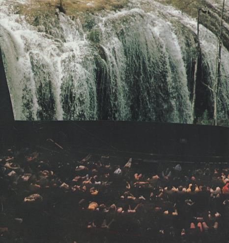 a group of theater goers watch a raging waterfall