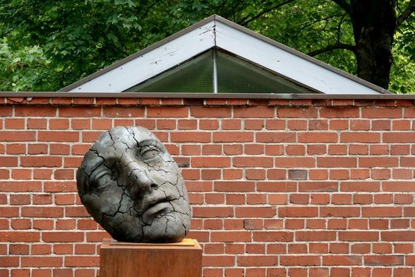 A stone mask in front of a brick wall