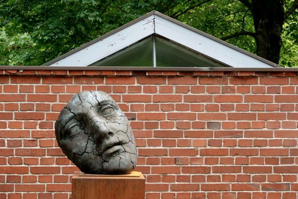 A stone mask in front of a brick wall
