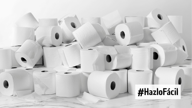 Fotografía monocromática. Decenas de rollos de papel higiénico blanco amontonados en una superficie de mármol. A su lado, el hashtag #HazloFácil.