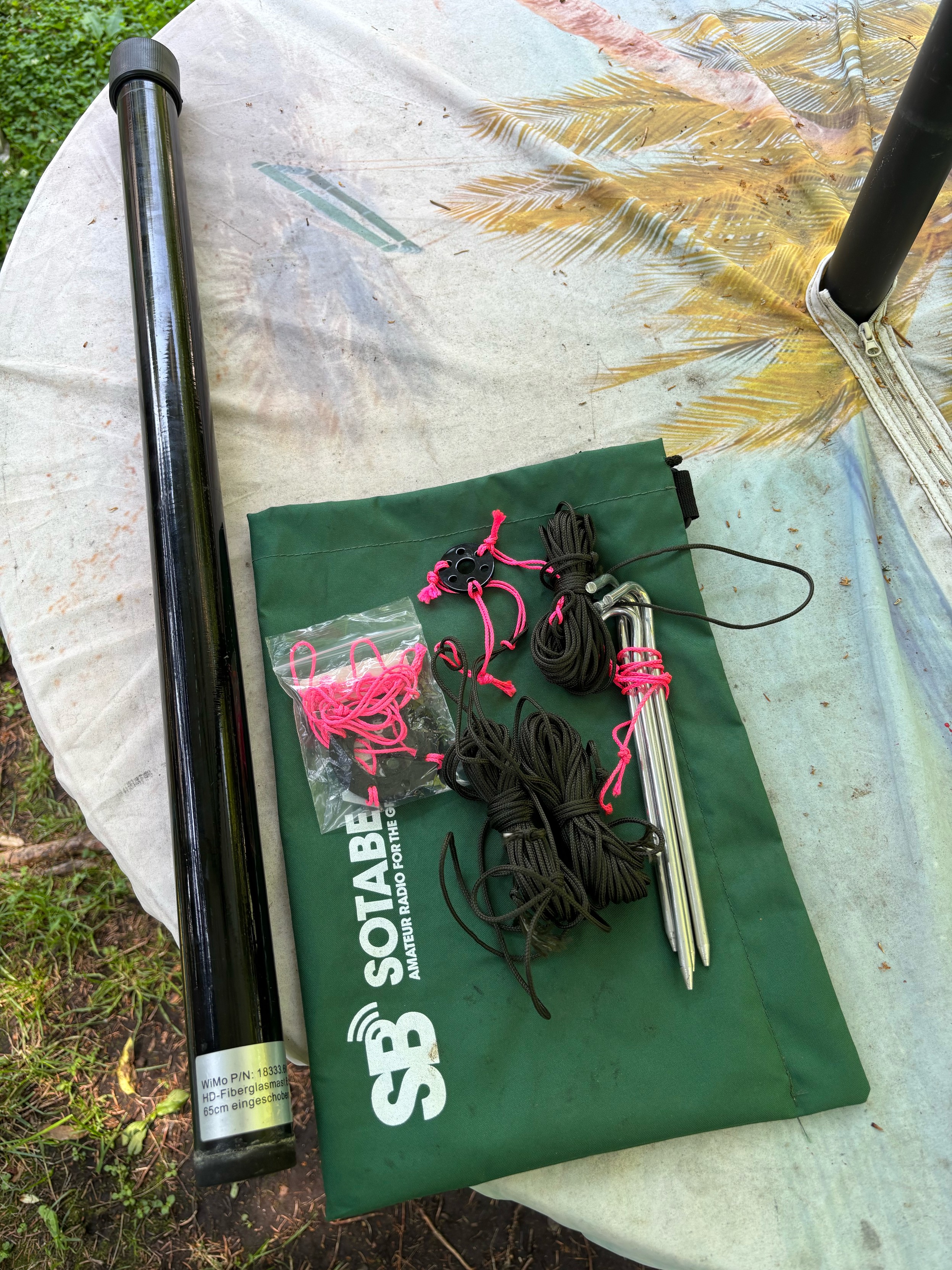 on table: collapsed antenna mast, bag with guying ring, ropes, stakes, and top-insulator.