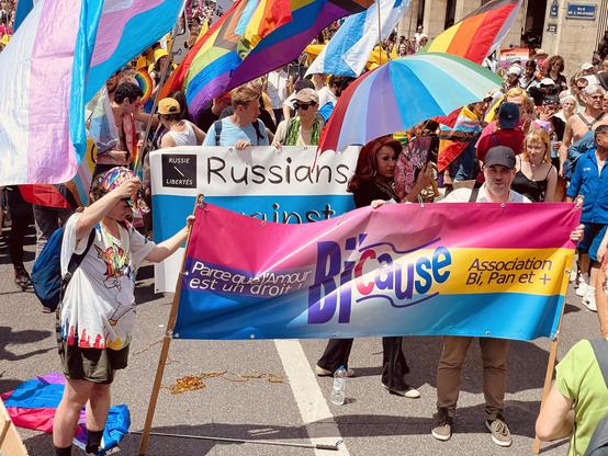 cortége, 2 personnes tenant la banderole de bi’cause, des drapeaux, foule