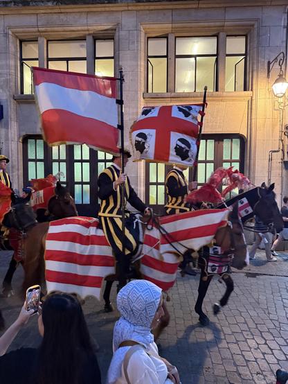 Horses with their riders holding a glad of Corsica and Austria