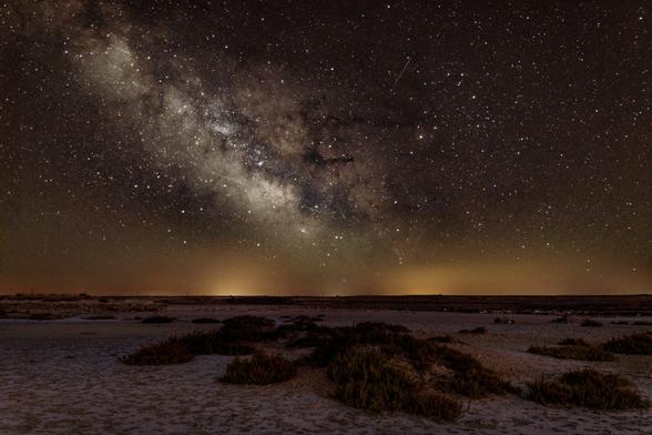 Photograph where in the lower third you can see part of the night landscape of the Monegros desert and above it a large starry sky with the Milky Way.
