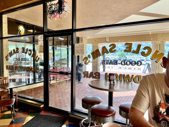 Looking out through the window of Uncle Sam’s Sandwich Bar. Large plate-glass windows and a glass door.