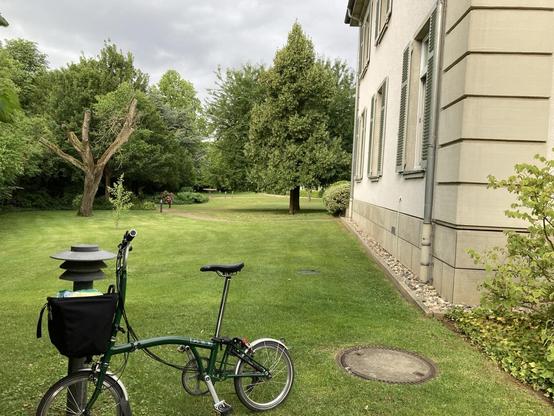 Folding bike in front of garden by classical building