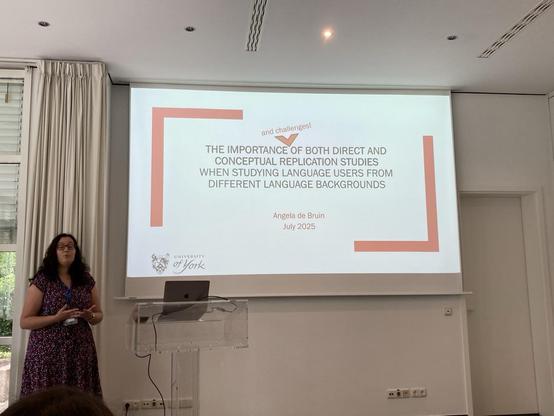 Angela presenting in a dress with the title of her talk shown on screen