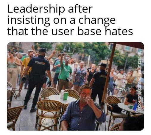 Picture of a guy drinking a beer under a tent, protected by security guards while a crowd looks on.

Caption: Leadership after insisting on a change that the user base hates
