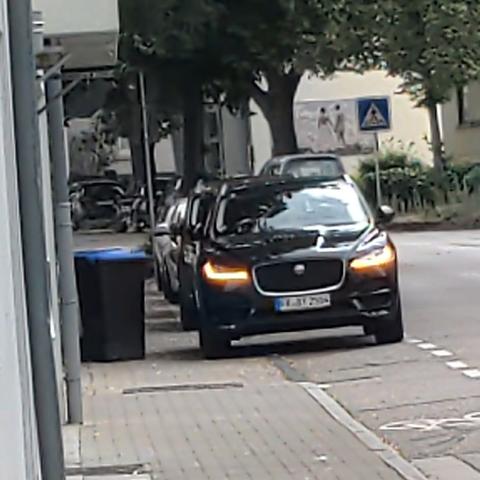 Ein Stadtpanzer von Jaguar sperrt gleichzeitig Gehweg und Schutzstreifen. Der Warnblinker ist gesetzt.