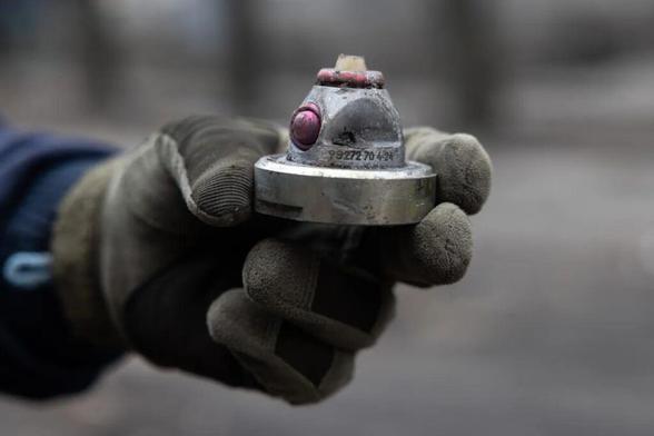 A Ukrainian deminer from the State Emergency Service shows a cluster bomb fragment after a large-scale Russian attack on a residential complex in Dobropillia, Ukraine, in March 2025