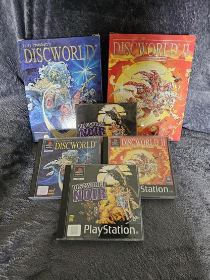 From top left to bottom centre: Discworld 1 (Big Box Edition PC CD-ROM), Discworld II (Big Box Edition PC CD-ROM), Discworld Noir (Jewel Case PC CD-ROM), Discworld 1 (PS1), Discworld 2 (PS1), Discworld Noir (PS1)