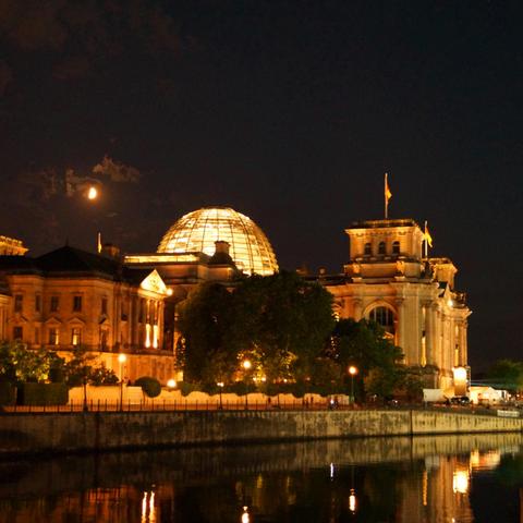 Der Reichstag bei Nacht mit Mond.