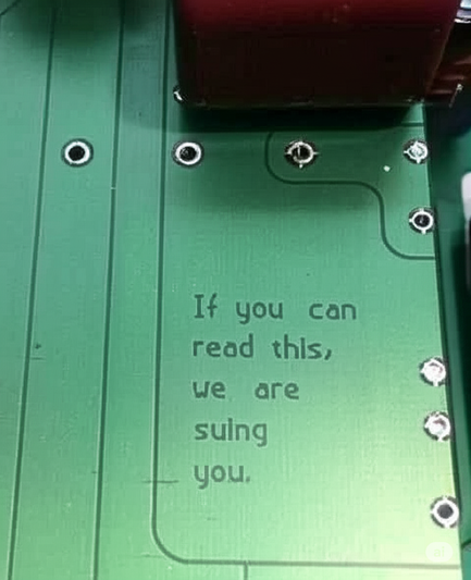 A photo of a circuit board

Text etched in the board:
"If you can read this, we are suing you"