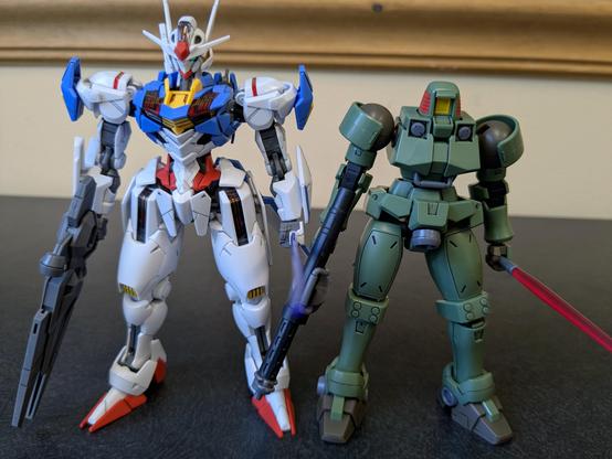 HGAC Leo standing beside HGTWFM Gundam Aerial. The top of Leo's head comes roughly to Aerial's shoulder.