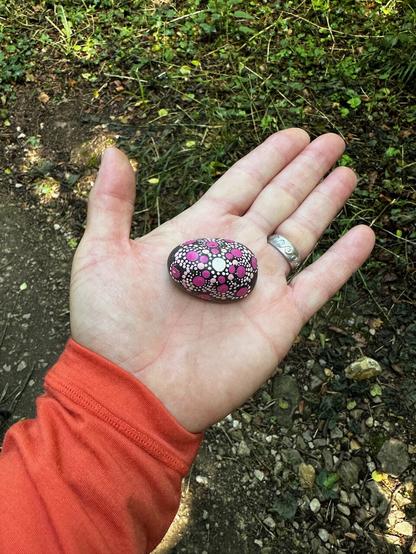 a white man's hand holding a rock with "for you with love" painted on it.