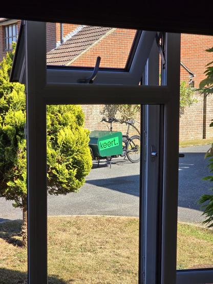 The same photo view out of the window as in the previous skeet but there is a green cargo bike with keert logos in the center