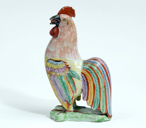“With plumage finely delineated in famille-rose enamels and gilding, his black beak open as if to crow, modeled standing on a green conformingly-shaped low mound base.”  “This model must have been taken from either a late 17th century Japanese Arita porcelain original…or equally likely, a Dehua blanc-de-Chine figure of circa 1700…Given the extensive trade by the Dutch East India Company (V.O.C.) with both Japan and China at this time, it is possible that either model served as the prototype for the present cockerel. The decoration is most likely to have been inspired by the early Chinese famille-rose porcelains of the Yongzheng Period (1723- 35). To achieve this delicate palette on tin-glazed earthenware, the enamels and gilding had to be fired at a lower temperature in a ‘muffle kiln,’ and the technique is referred to as ‘petit feu.’”