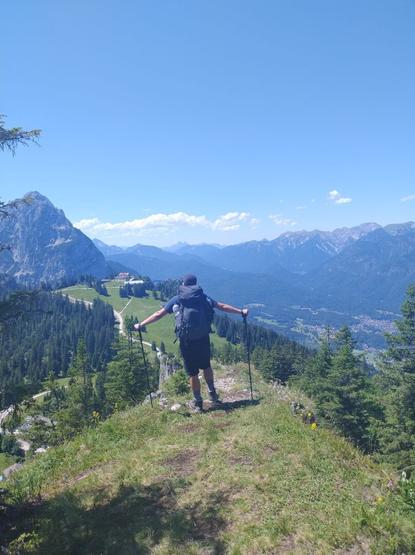 You can see me from behind with an oversized backpack on the edge of a cliff watching the scenic mountains and this hike's goal: the Kreuzeckhaus