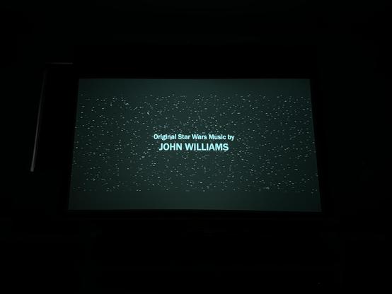 Projection screen showing a field of stars and credits in the middle that read original Star Wars music by John Williams