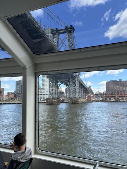 Cool angled windows on the cruise around Manhattan. Here we’re going under a bridge, don’t know which. The back of someone’s head is seen, also looking out the window.