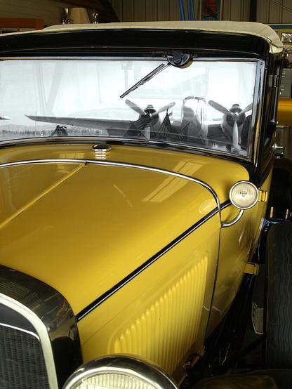 Reflection On The Past

This is an image of an old Model owned at the time by WWII flying ace Duncan Miller. 
The front grill sits in the left corner of the image. The frame of the radiator is chrome as is the circular headlight frame. The model A is painted a brilliant yellow with chrome highlights in many places. The side of the front fender has gill like vents.
Reflected in the window of this convertible is Duncan Millers C47 that he flew in World War Two. I took liberties and did some selective coloring in the window frame.