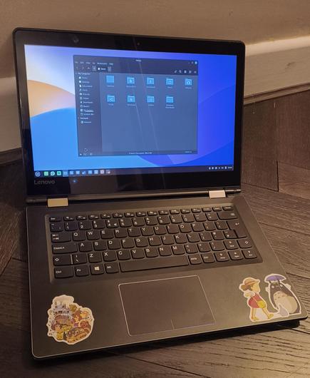 A Lenovo Yoga from 2017, running dark mode Linux Mint with some Studio Ghibli stickers below the keyboard.