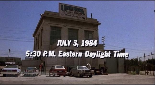 An industrial building with a sign reading “UNEEDA MEDICAL SUPPLY,” with cars parked outside. Text overlaid states, “JULY 3, 1984 5:30 P.M. Eastern Daylight Time.”