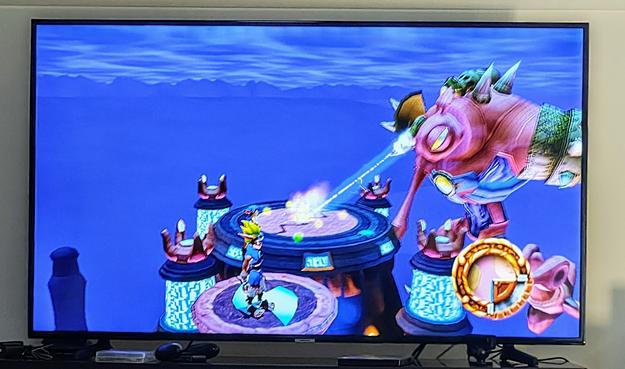 A screen showing Jak and Daxter in their final boss fight against the giant Precursor Robot. The robot is firing a beam of destructive light onto the platform below.