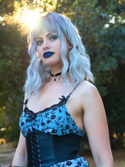 Portrait of a woman with blue lipstick and eye shadow from the waist up. https://www.instagram.com/GothiccRoze