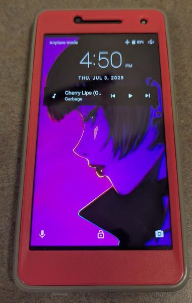 A photograph of a Blue R1 HD phone.  It is in a pink and gray case with a background of an anime woman in profile.  The picture is all purples or black.  Very striking in person.  The time and other negligible Android Marshmallow bits and bobs are around, but it is showing a push notification from a music app.  The song playing, that is currently paused as I put it there for display purposes, is Cherry Lips (Go Baby Go) by the band Garbage.  It's hella queer and excellent.