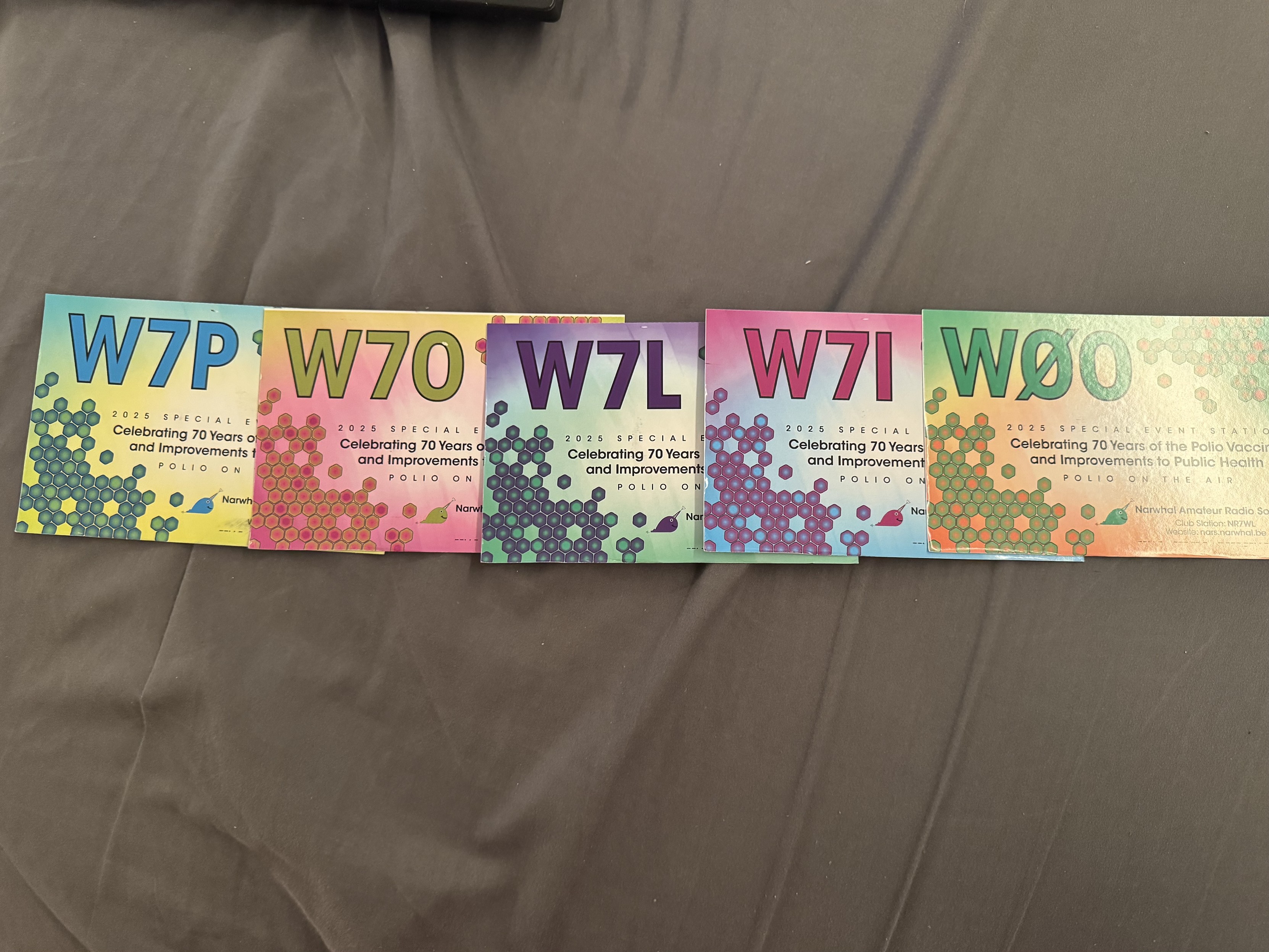 Brightly colored QSL cards from ham radio stations W7P, W7O, W7L, W7I, and W0O, part of the Polio On The Air event marking 70 years of the polio vaccine