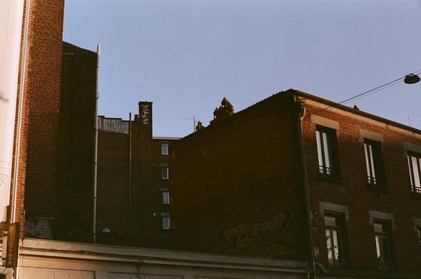 Colored photography of red bricks buildings top on blue sky background. some of the buildings are in the shade, a ray of light is lighting the top of them.