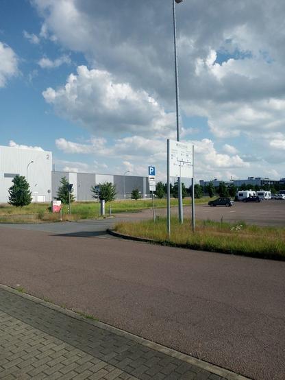 Industriegebiet. Campingwagen stehen auf einem großen asphaltierten Parkplatz. Halb bewölkter Himmel.