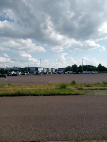 Industriegebiet. Campingwagen stehen auf einem großen asphaltierten Parkplatz. Halb bewölkter Himmel.
