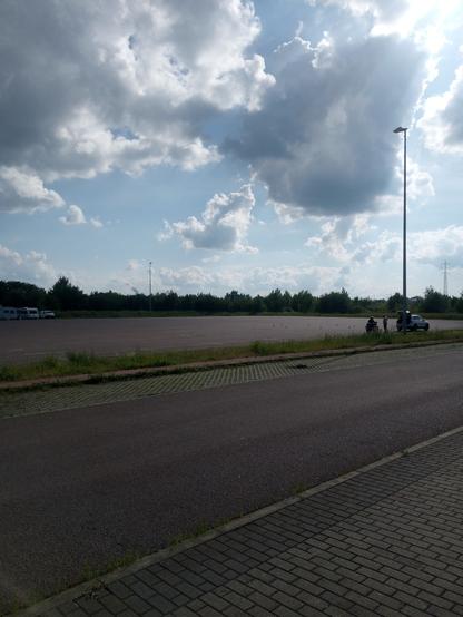 Industriegebiet. Campingwagen stehen auf einem großen asphaltierten Parkplatz. Halb bewölkter Himmel.
