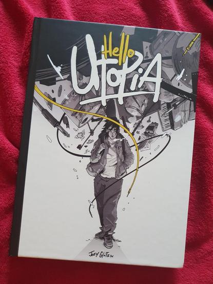 Couverture de la BD "Hello Utopia" de Joey Glüten, avec une jeune femme habillée en vêtements larges, avec un sac à dos et une cigarette à la bouche. Au dessus d'elle gravitent des câbles et des instruments de musique (élements d'une batterie, piano).