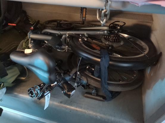 Photo d'un vélo pliant plié, muni de sa petite étiquette réglementaire, dans l'espace bagage d'un train