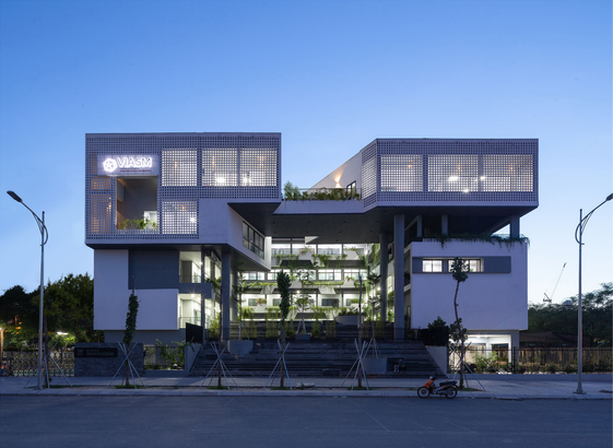 A picture of a beautiful modern building against a luscious green backdrop and open blue sky. This is the VIASM building where the conference will be hosted.