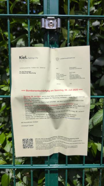 Aufforderung Räumung wegen Bombenentschärfung
Ist an einem Zaun befestigt
Dahinter grüne Hecke