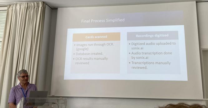 Mike presenting a slide that reads:

Final Process Simplified
Cards scanned
• Images run through OCR.
(google)
• Database created.
• OCR results manually reviewed
Recordings digitized
• Digitized audio uploaded to sonix.ai
• Audio transcription done by sonix.ai
• Transcriptions manually reviewed.