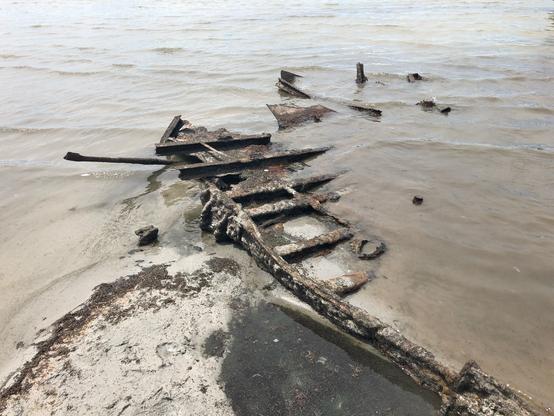 The rusted skeleton of a 30- to 40-foot steel and wood boat sits mostly buried and submerged in the salty waters of the Great Salt Lake in Utah, USA.