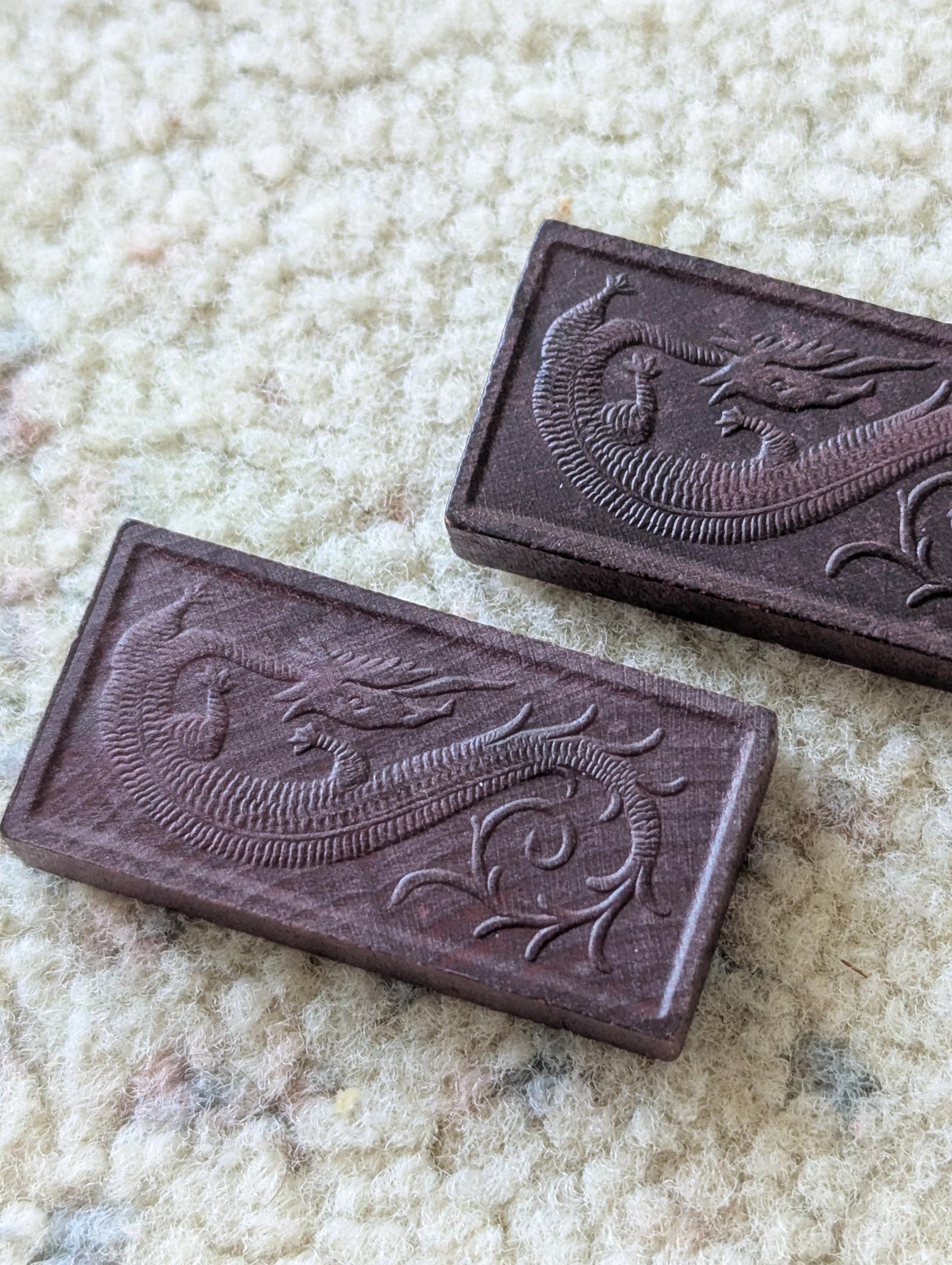 Two small wooden dominoes with a lovely dragon pattern embossed on the back