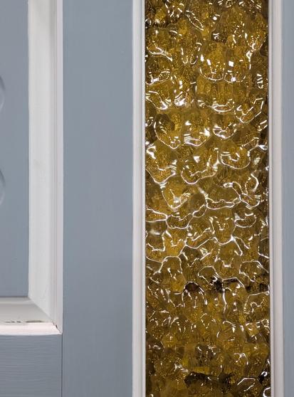 partial view of an old door, painted matte pale blue and white, with a glossy pane of rippling yellow glass