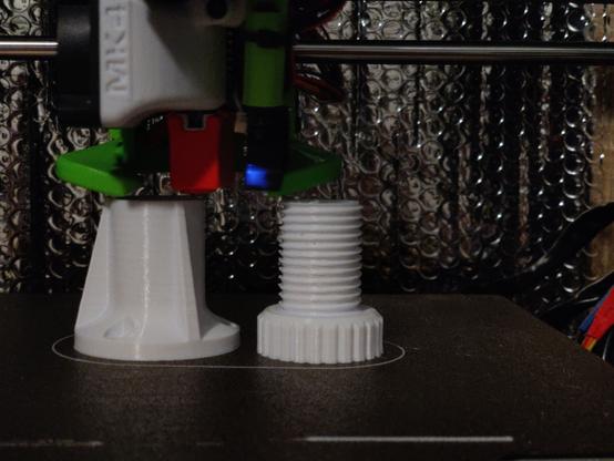 Close up of a 3D printer working on an adjustable foot for furniture.